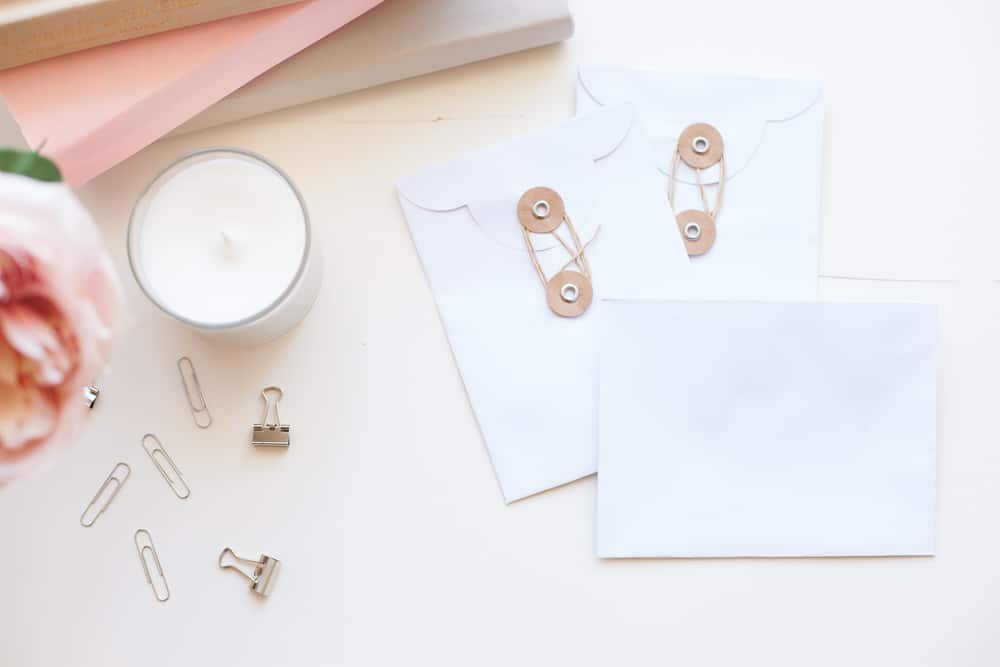 envelopes, paperclips, a candle and a flower on a desk