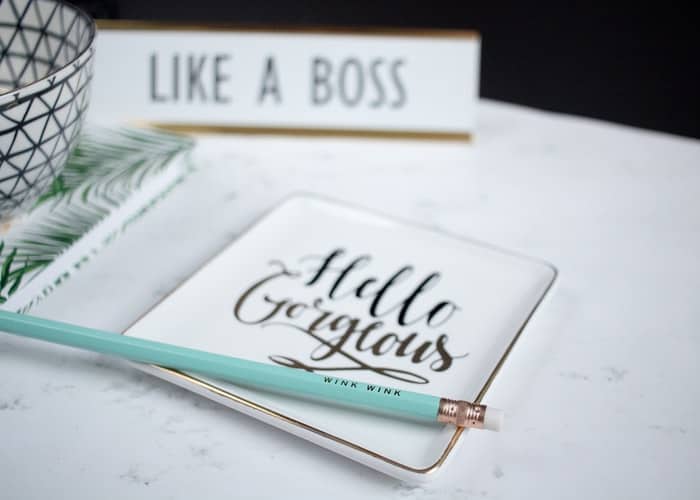 A coaster that says "hello gorgeous" with a pencil on top