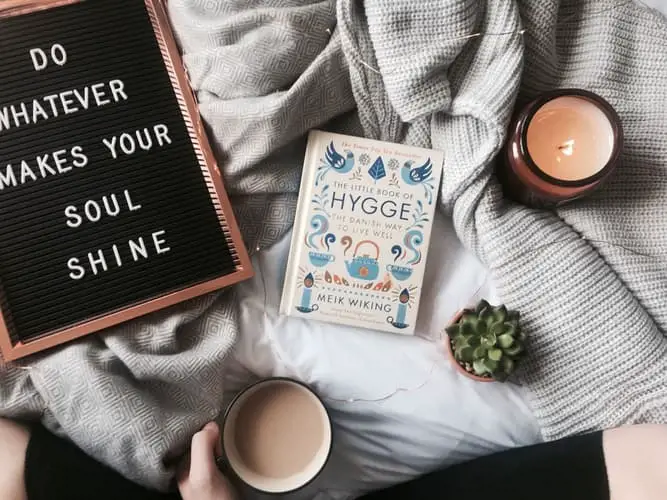 A book on Hygge, hand holding a mug, and message board that says "whatever makes your soul shine"