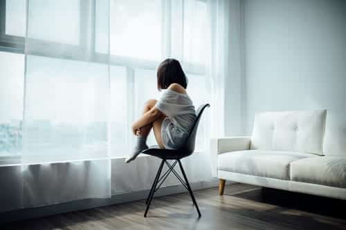 A person sitting on a chair staring out of the window