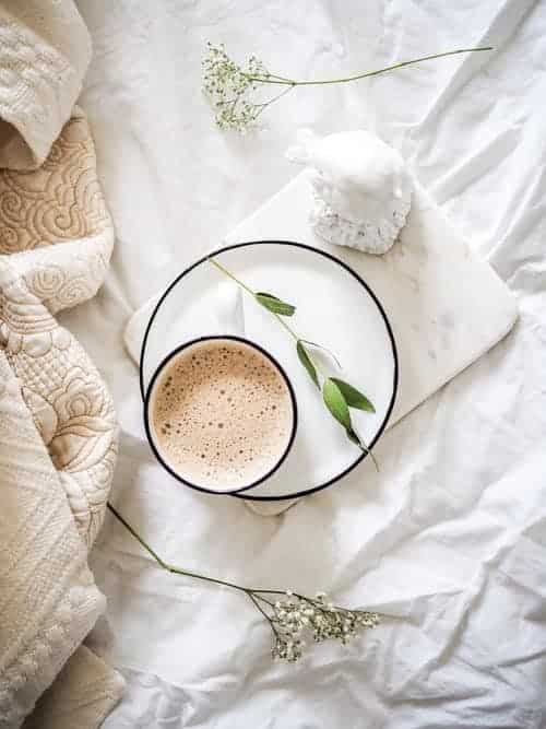 A mug of hot coffee on a bed