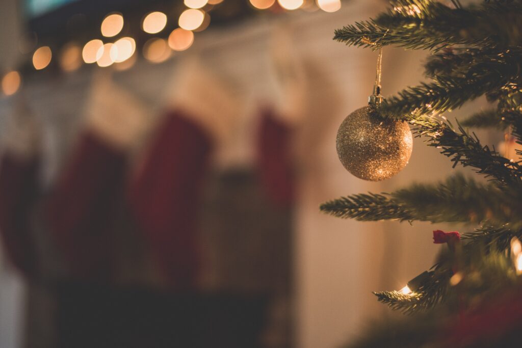 A Christmas tree with a gold bauble and fairy lights in the background