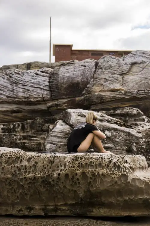 A girl sitting on the edge of a rocky ledge