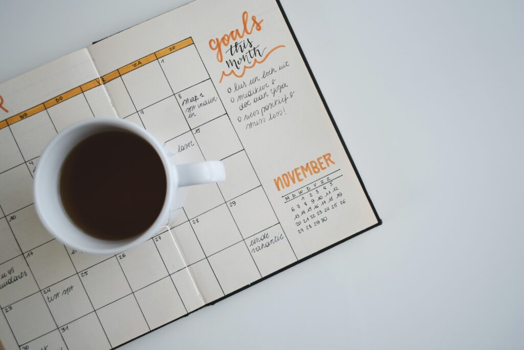 An open planner that's been filled out with a cup of coffee resting on top