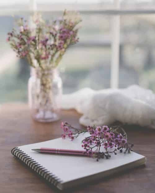 notepad and pen on a table with purple flowers