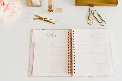 goal setting journal open on a desk with paperclips, scissors and a flower