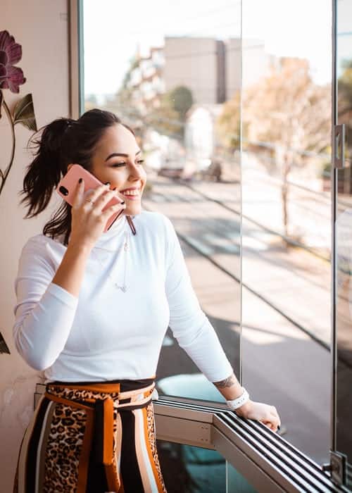 woman smiling out of a window while on the phone