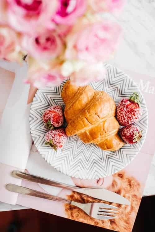 A croissant and strawberries on a plate