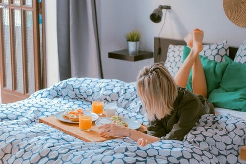 A woman laying on her front in bed next to a breakfast tray