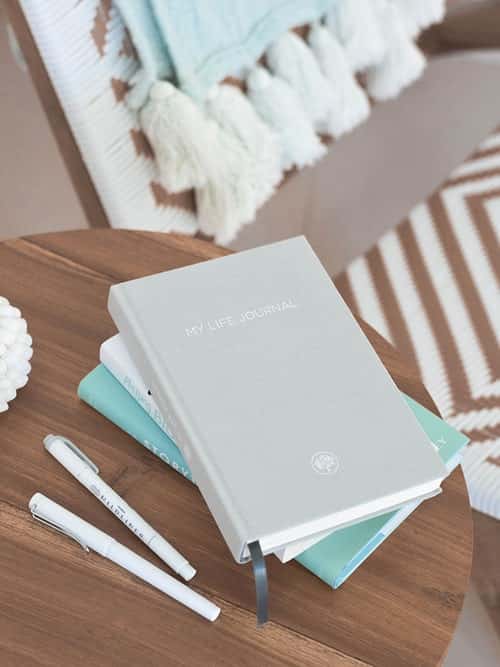 stack of journals on a small table next to a chair