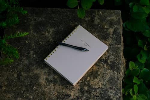 A closed journal and pen on a stone wall