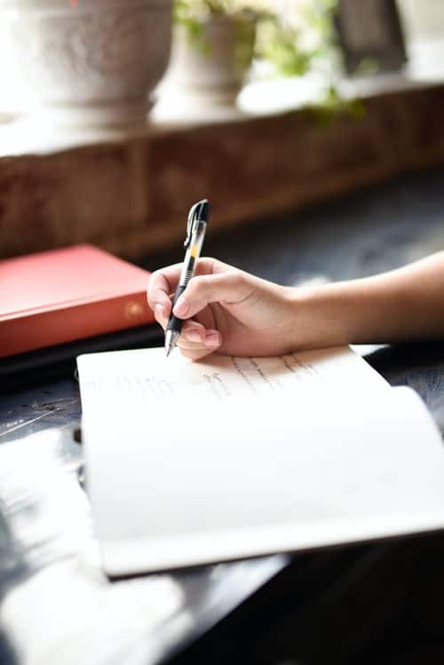 a woman writing in a journal at a desk