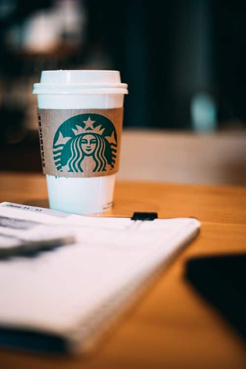 a Starbucks cup on a table next to paper
