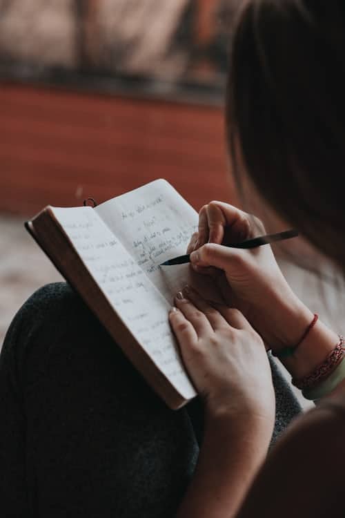 Someone sat on the floor writing in their journal.