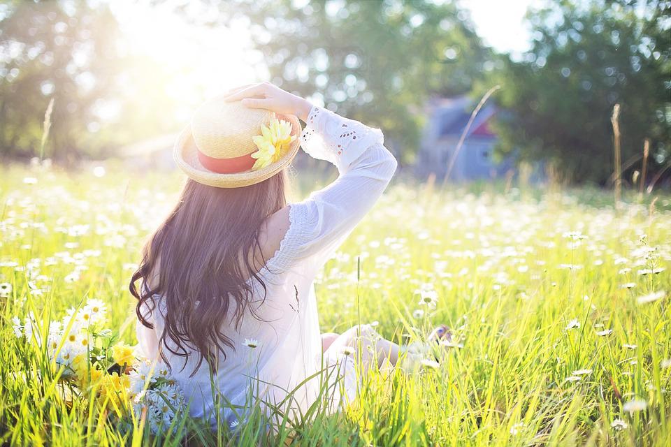 A woman in a field; the sun is shining 