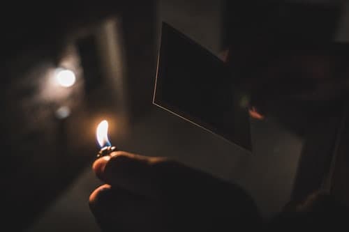hands about to set fire to a polaroid with a lighter