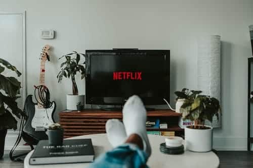 Someone with their feet up on a table watching Netflix on their TV