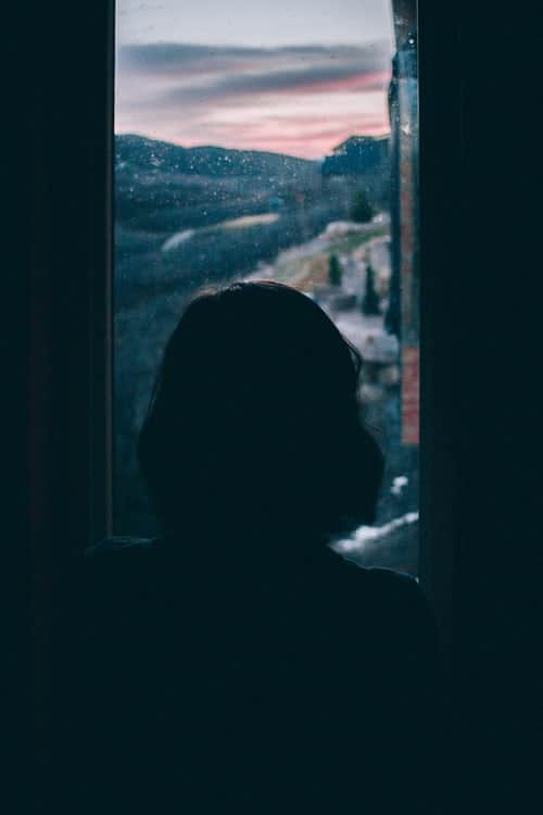 The silhouette of a woman staring out of a window