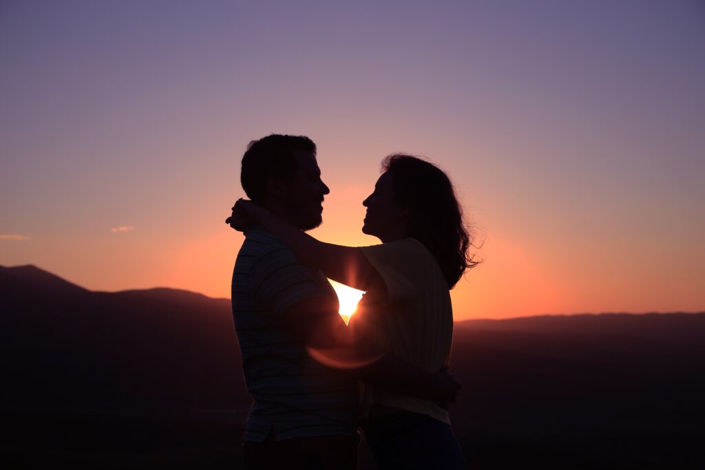 Two people embracing silhouetted against a sunset