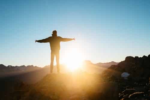 A person standing on top of a mountain with their arms out