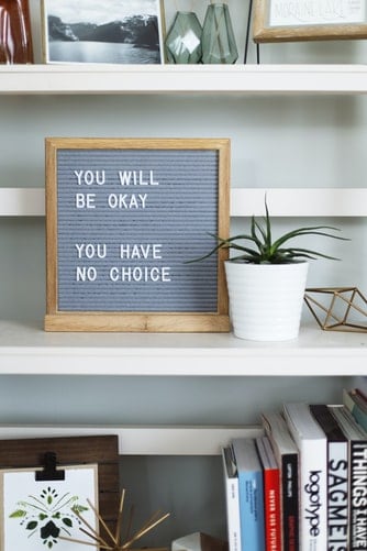 A message board on a shelf reading, "you will be okay, you have no choice"