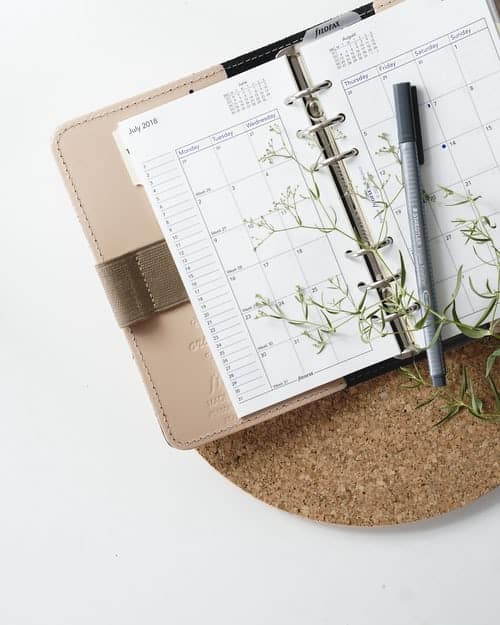 An open planner on a desk with a pen