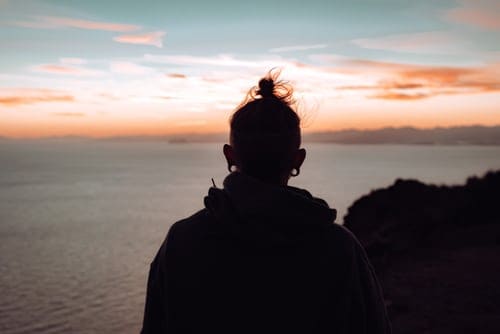 a person standing on a cliff watching the sunset