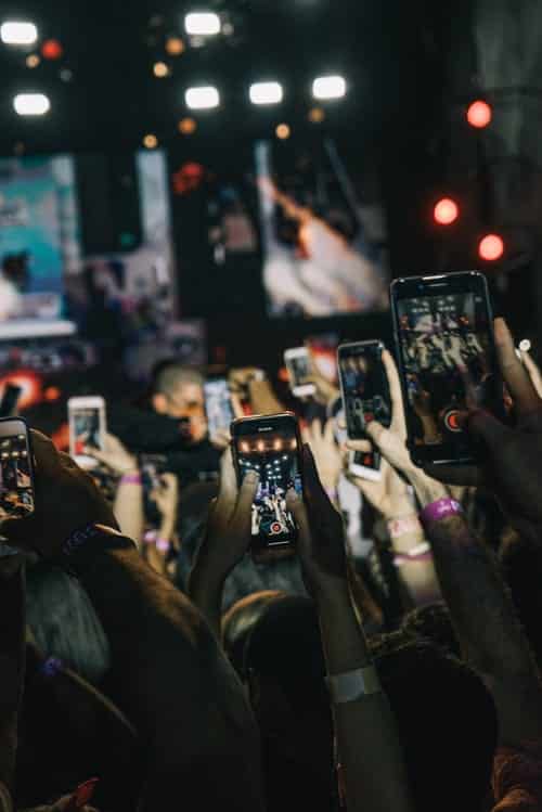 multiple people filming a concert with their phones