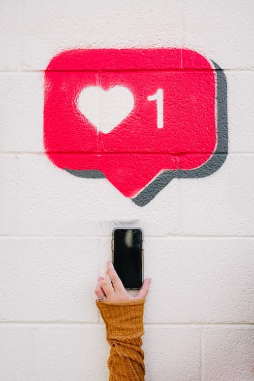 The Instagram 'like' alert icon painted onto a wall; someone's taking a picture of it on their phone
