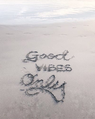 "Good vibes only" written in the sand at a beach