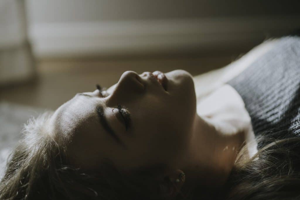 A woman laying down staring at the ceiling