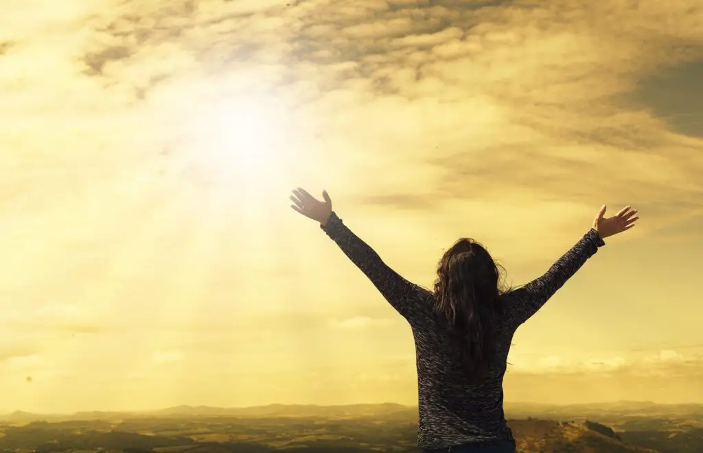 A woman with her arms raised toward to sun.