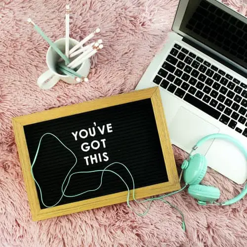sign board, headphones and a laptop on a fluffy blanket; the board reads "you've got this"